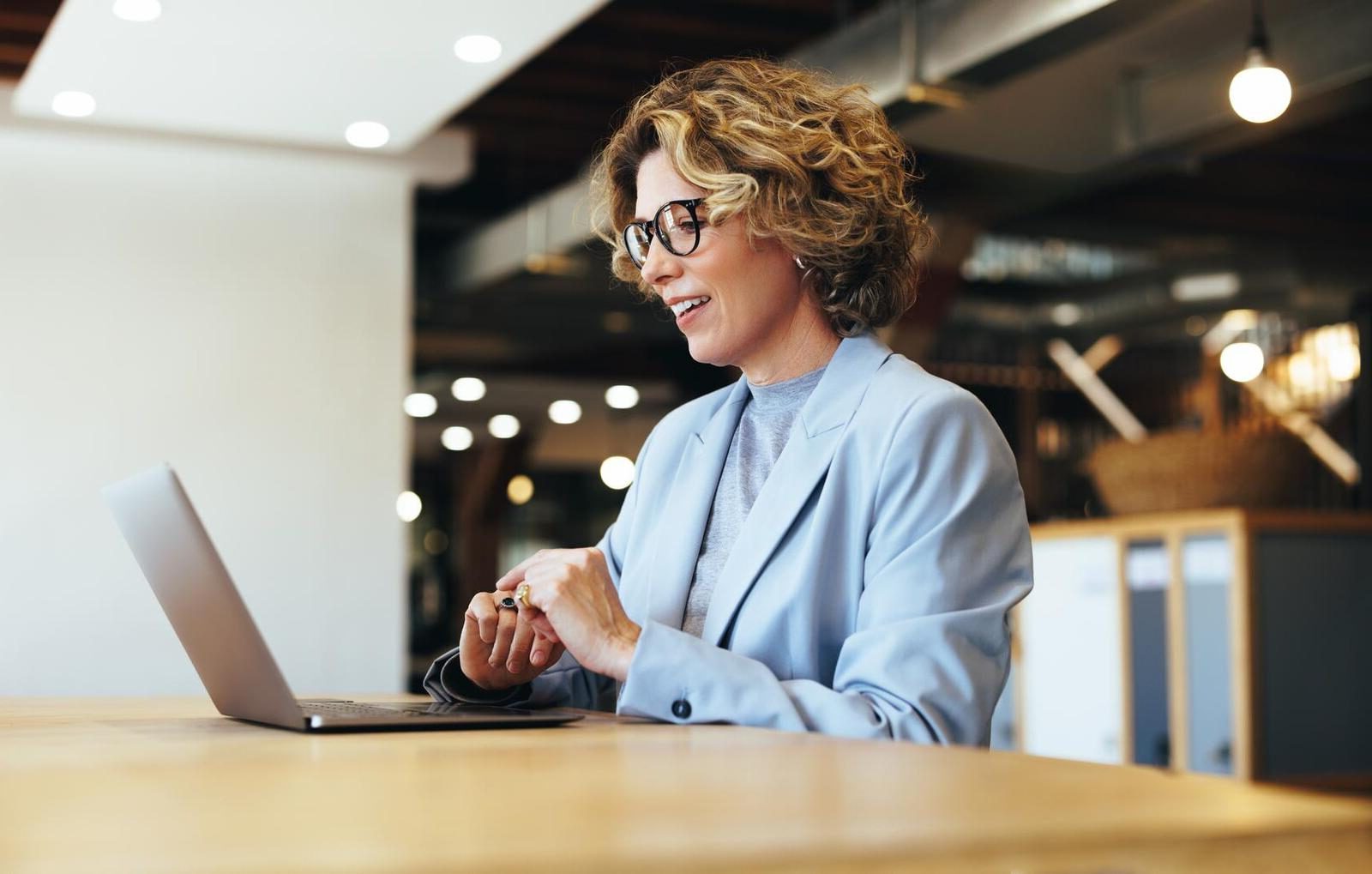 Vrouwelijke financieel adviseur met bril en lichtblauw colbert in gesprek via laptop, passend bij helder zzp advies.