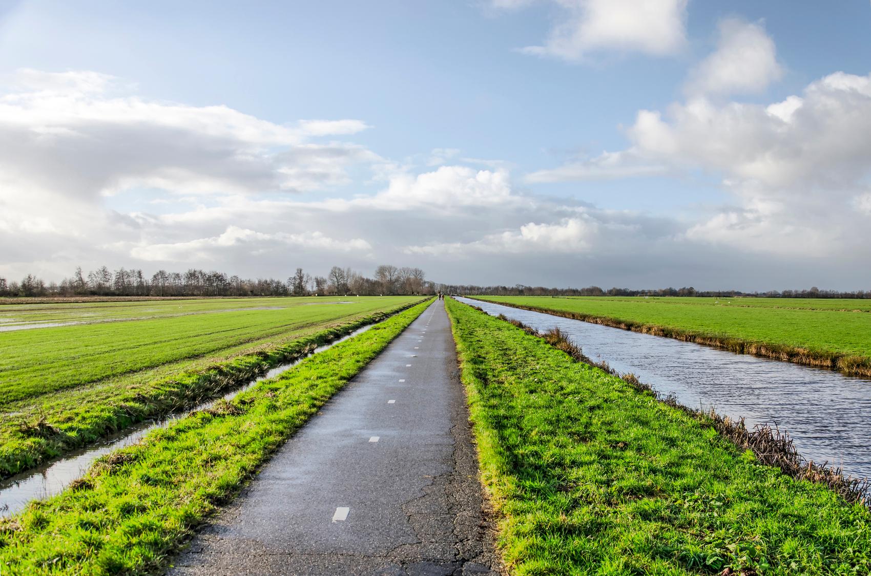 Lang fietspad door polderlandschap bij Ouderkerk aan den IJssel met sloten aan weerszijden.