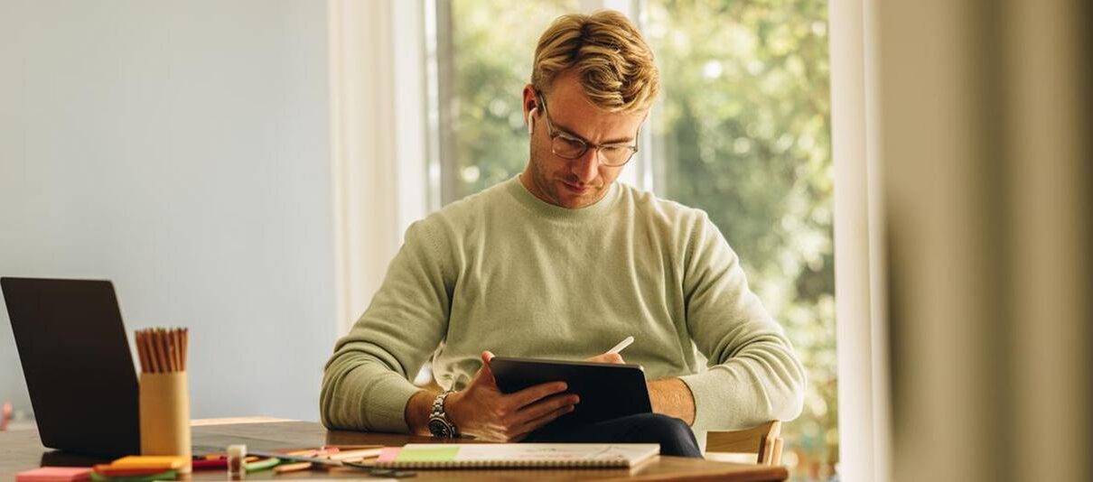 Jonge man achter zijn tablet om schade te melden bij een verzekeringsadviseur.